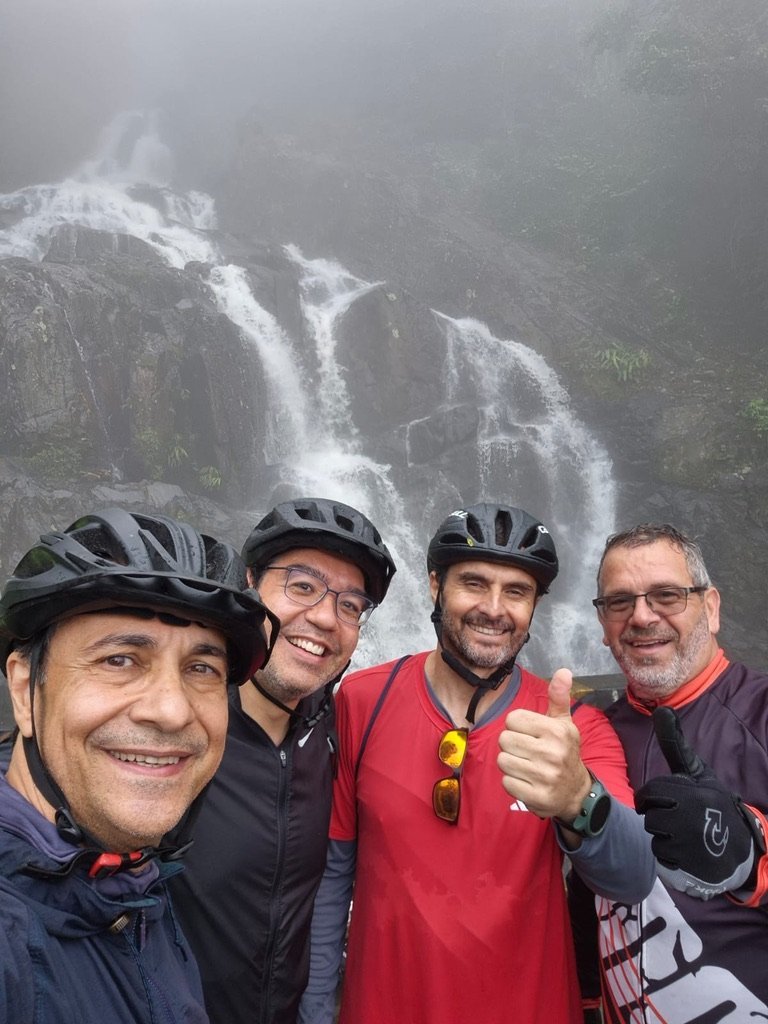 Quatro participantes diante de uma cachoeira em meio à neblina