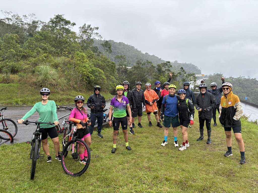 Grupo reunido com bicicletas na serra sob céu nublado