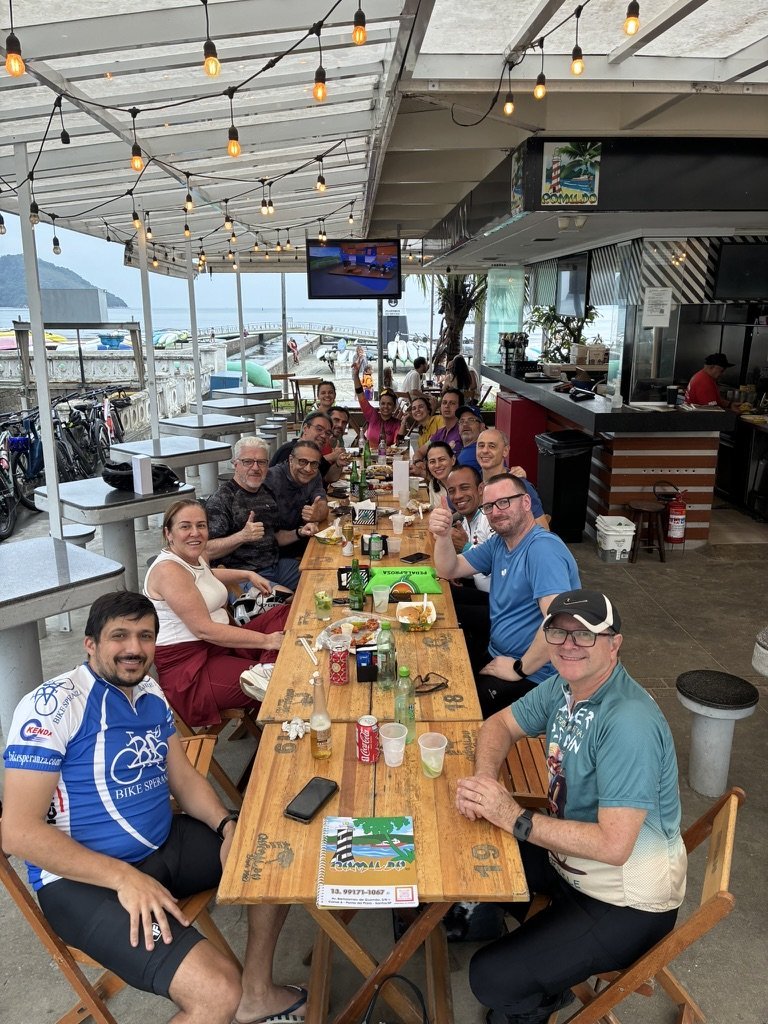 Participantes reunidos à mesa com vista para o mar