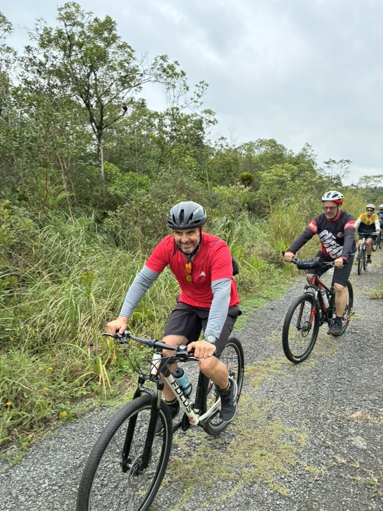 Ciclistas pedalando em caminho cercado de vegetação